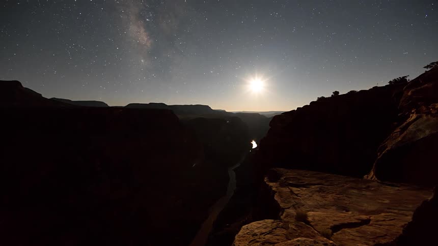 The moon sets over a river canyon