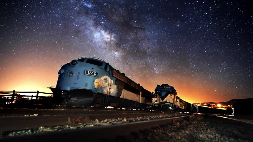 Train parked on tracks and stars soar overhead