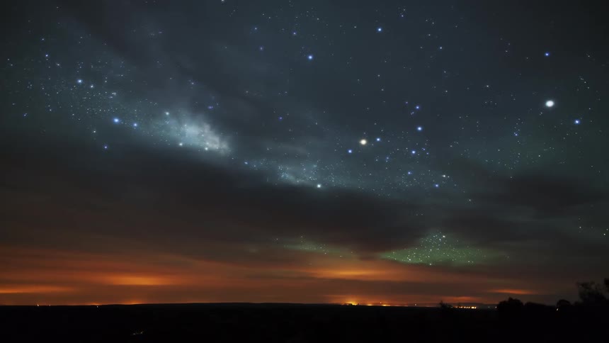 Clouds float by in a starry night sky