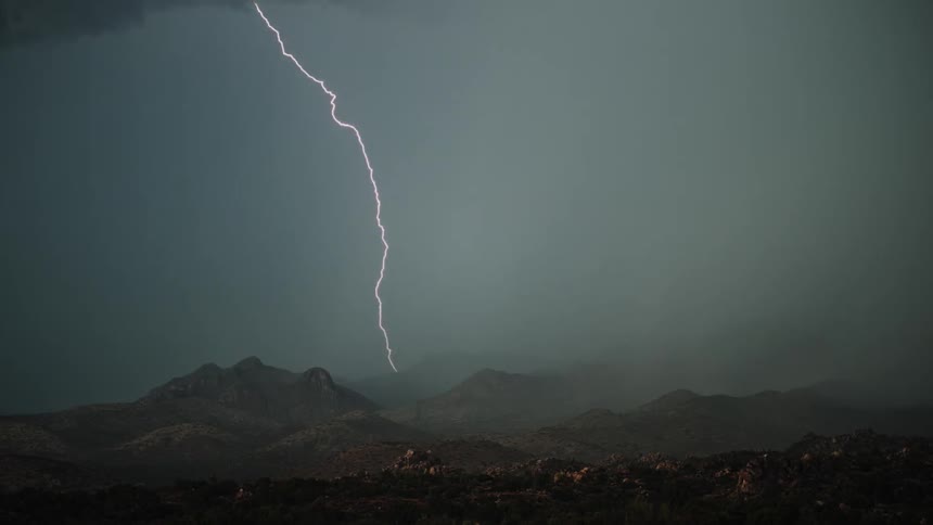 A lightning storm lights up the sky and dumps rain over a mountain range