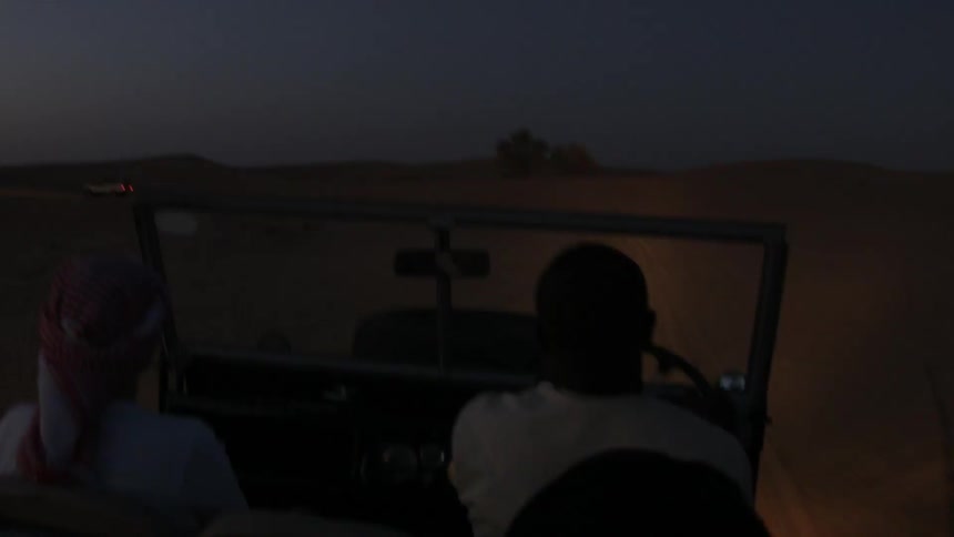 A man is driving through a dark desert
