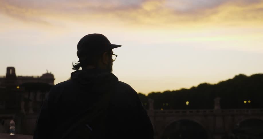 Man looking out at a city at sunset