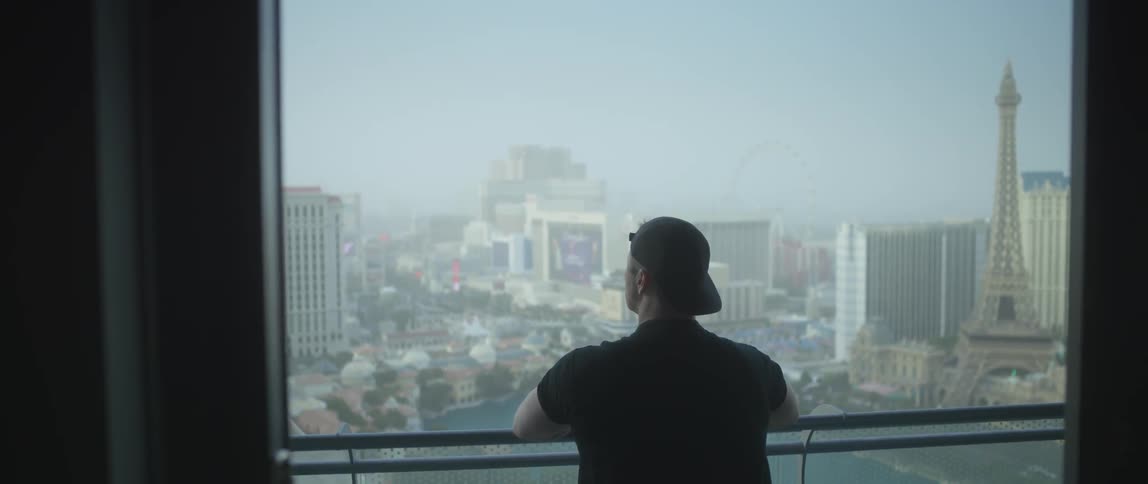 Man stands by a railing overlooking a city below