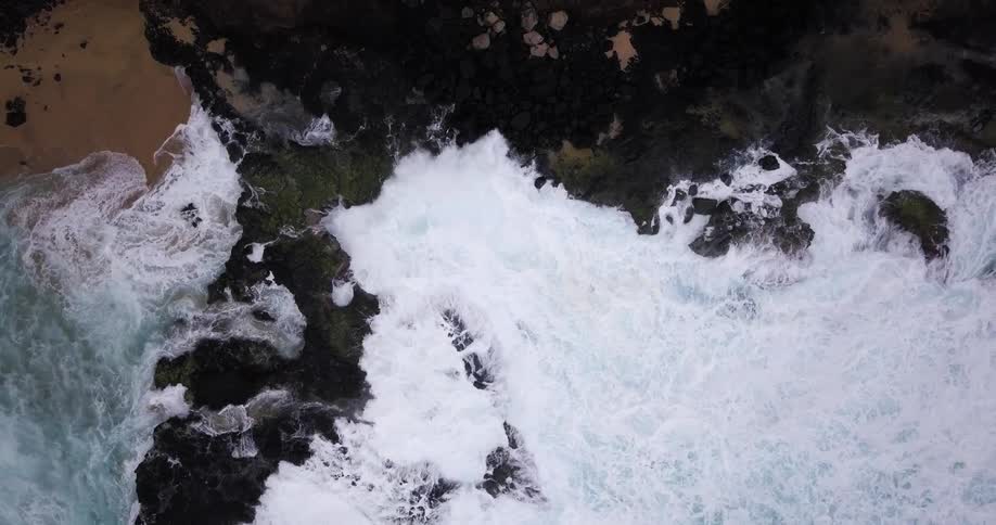 Large waves crash against the rocks on the shore