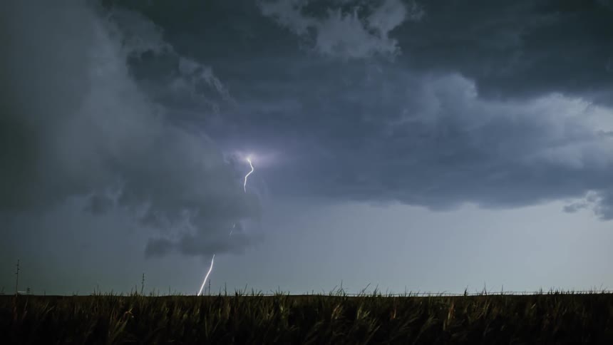 Lightning strikes from storm clouds over a field