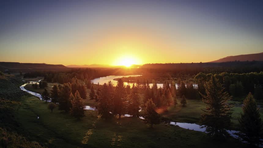 Sun rising over a stream and trees