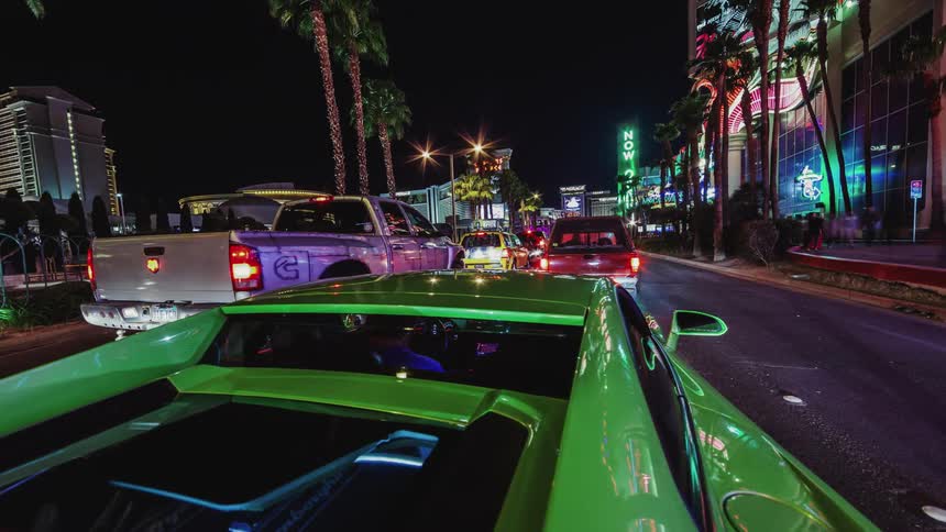 A person is driving a sports car down a city street at night