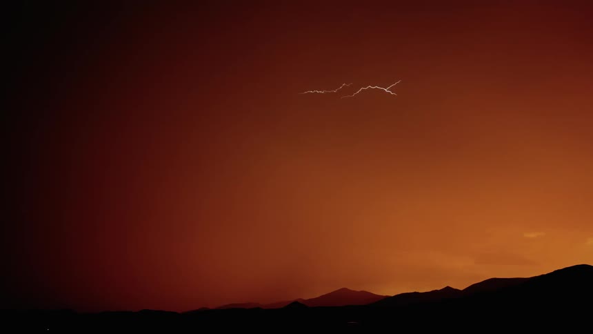 Lightning flashes and moves within the body of a storm at dusk