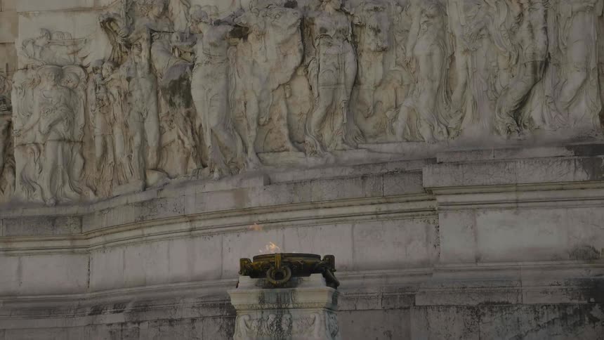Fire burns in front of an ornate carved wall