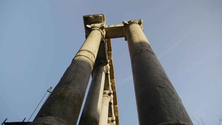 The sun shines down on tall stone pillars