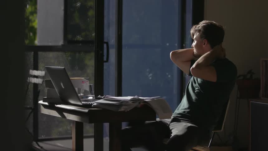 A man hangs up his phone and looks out the window