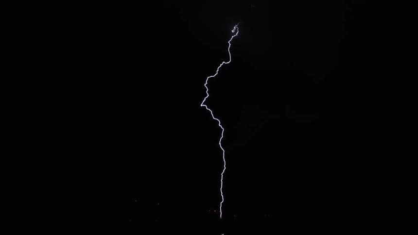 The night time sky flashes with lightning