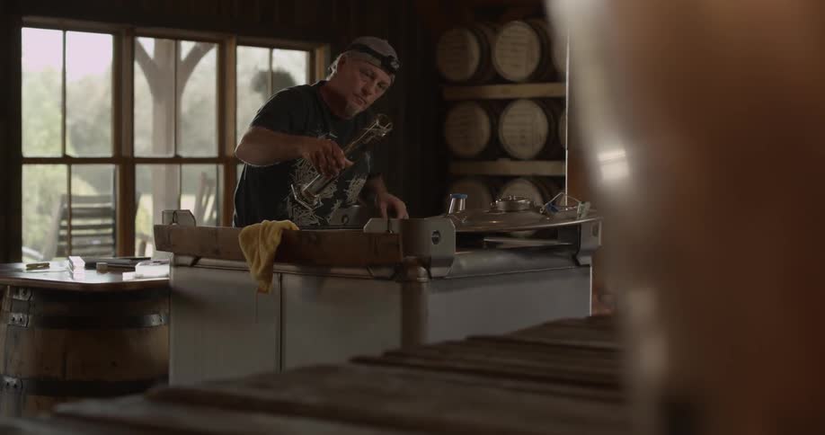 A man lifts up a vial full of beer in a distillery