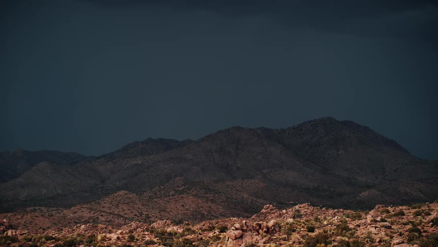 Lightning strikes behind a desert hill
