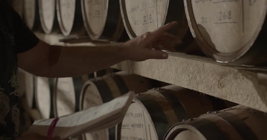 Man checks clipboard in front of a large wall of barrels