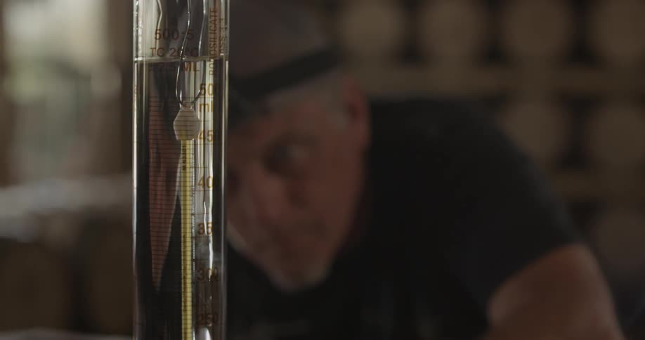 A worker examines fluid in a graduated cylinder