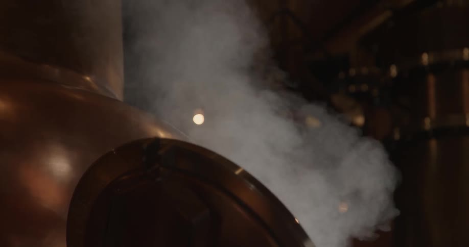 Steam rises up from a large kettle in a workshop