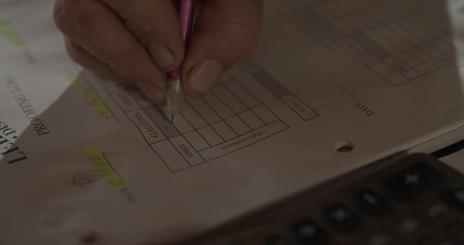 A person writes on paper with a pen