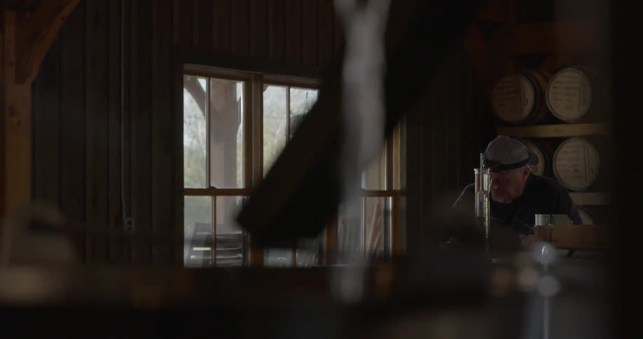 Water flows from a tap in a barrel room where a man is working