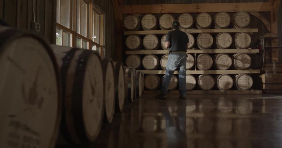 A man walks around a distillery making notes