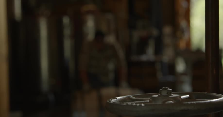 A man rolls a barrel through a workroom