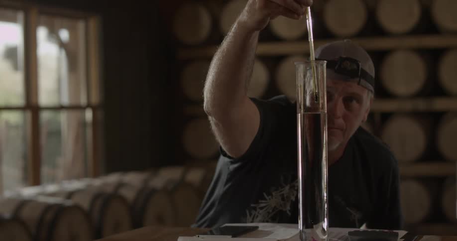 A worker measures liquid in a graduated cylinder
