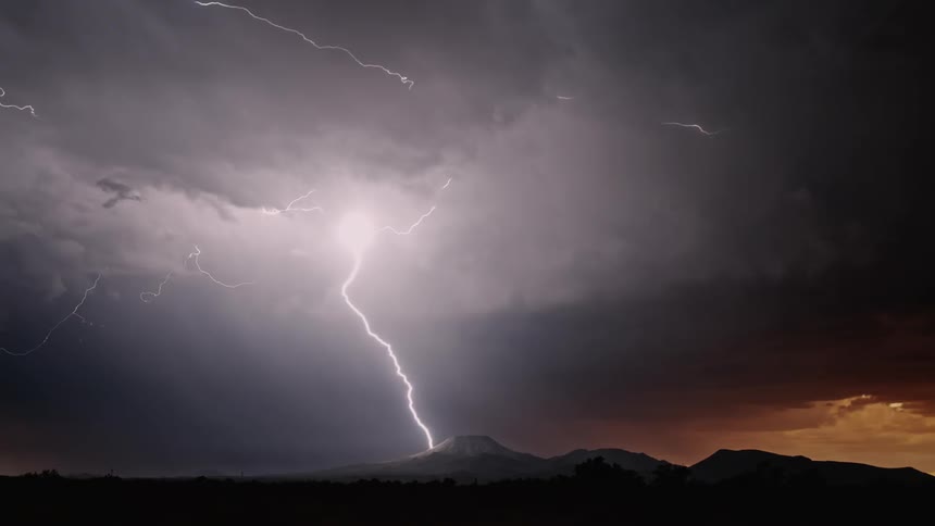 Lightning strikes a hill at sunset