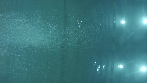 Air bubbles float in a lit swimming pool