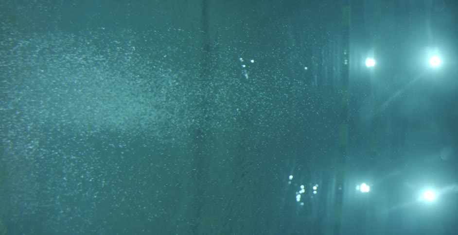Air bubbles float in a lit swimming pool