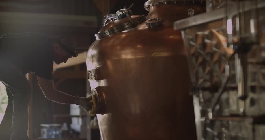 Man polishes large brass kettle