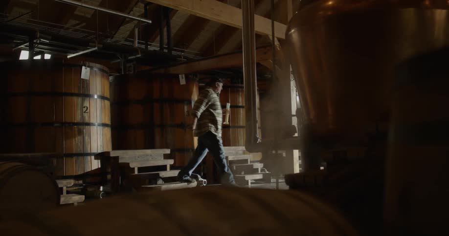 Man reaches into a large barrel and takes out a beaker