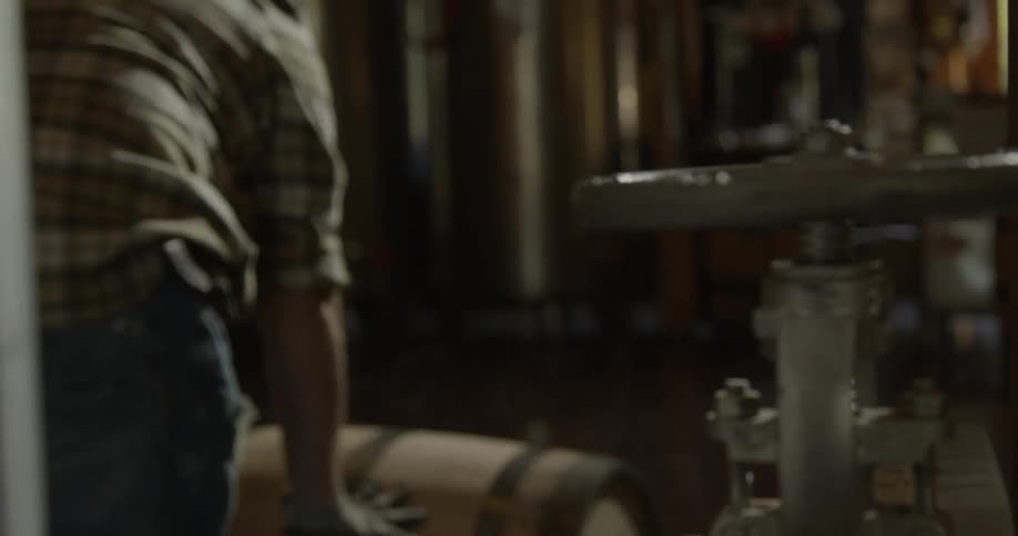 A man rolls a barrel through a storeroom