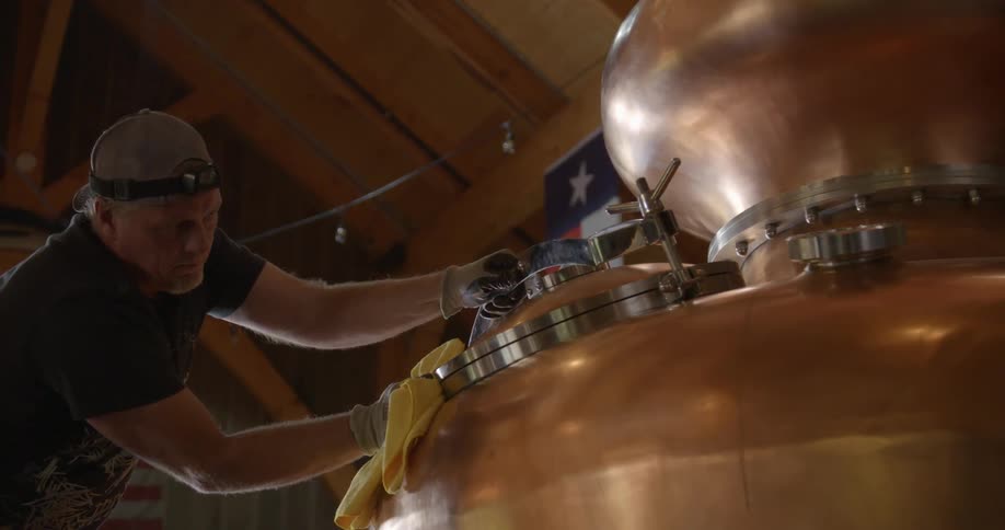 Man polishes large brass kettle