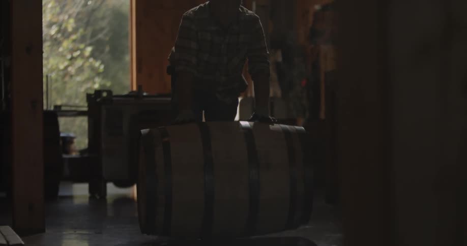 A man is working pushing a barrel