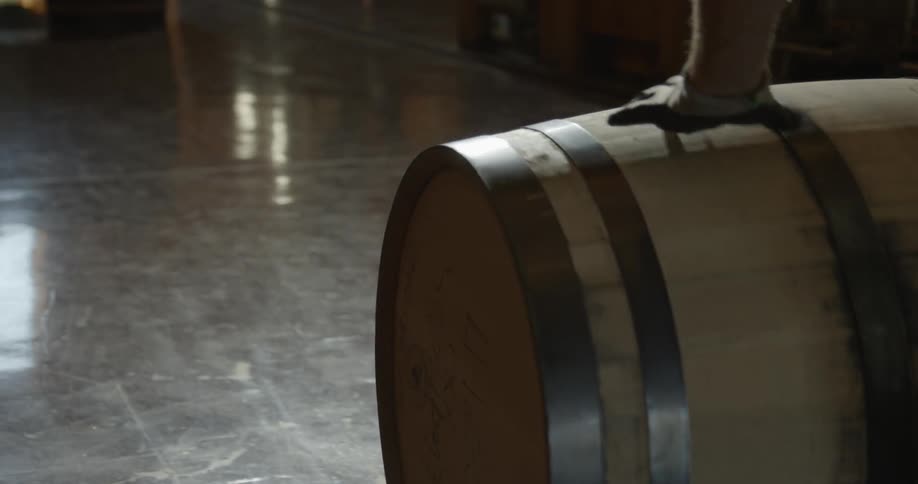 A man rolls a wooden barrel across the floor