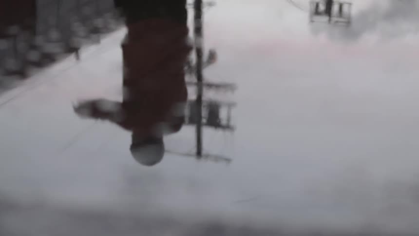 A person with a jump rope and their reflection in a water puddle