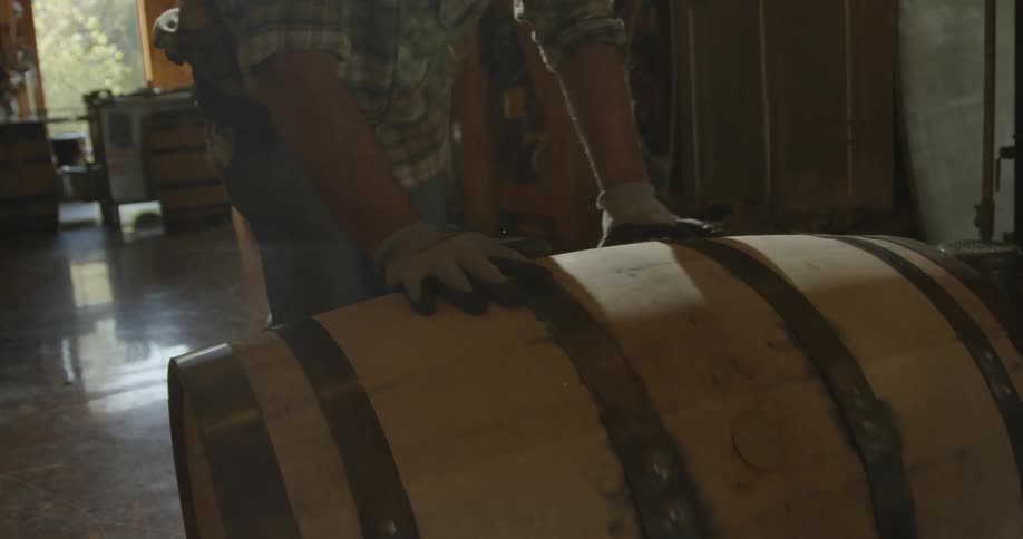 A man rolls a barrel in a distillery
