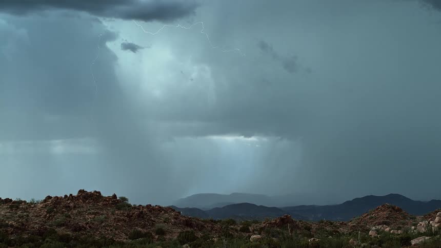 The sky is covered with grey storm clouds raining and flashing lightning