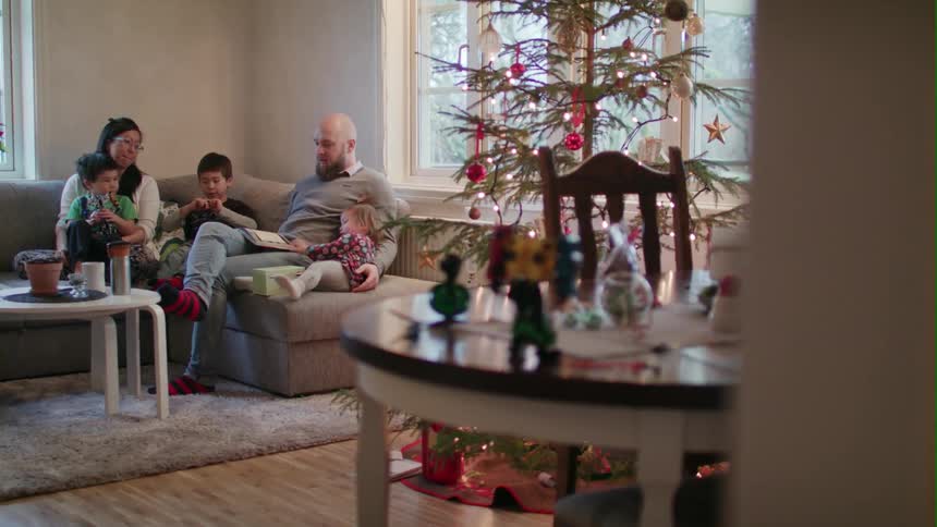 A family sits on a living room couch at christmastime