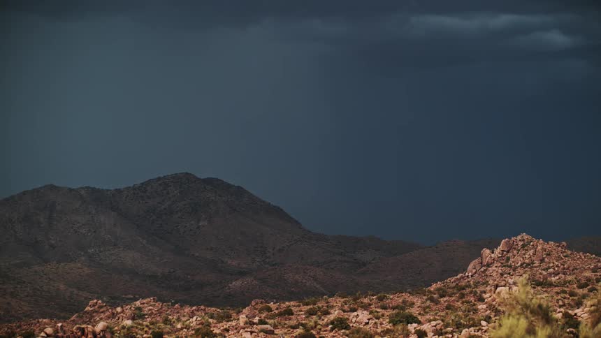 Lightning flashes over a desert hill