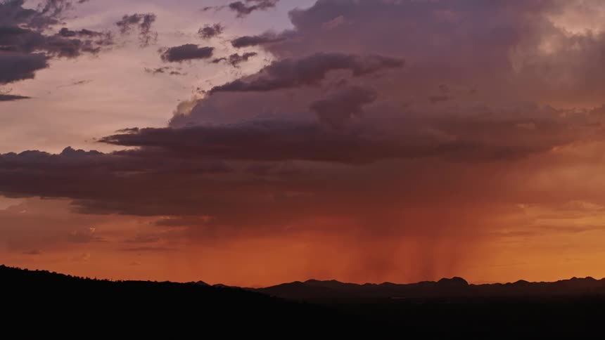 The rain clouds are red with color and pouring rain at dawn