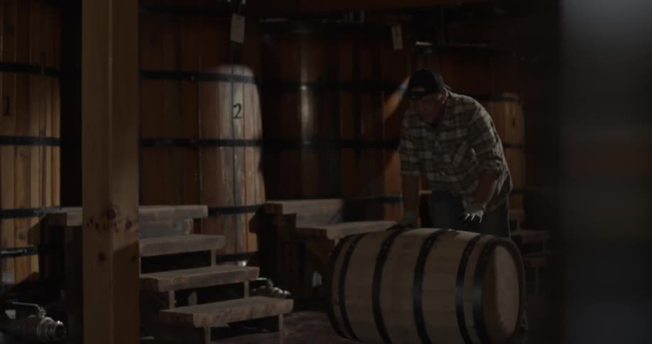 A man rolls a barrel along the flow in a brewery or distillery