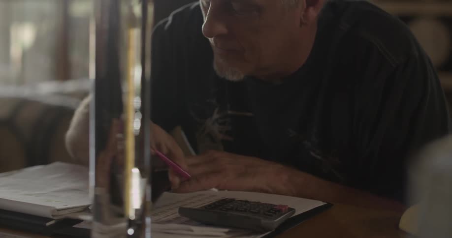 Man writes something in a notebook looking at a glass beaker