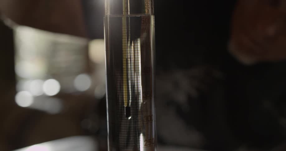 A man measures liquid in a graduated cylinder