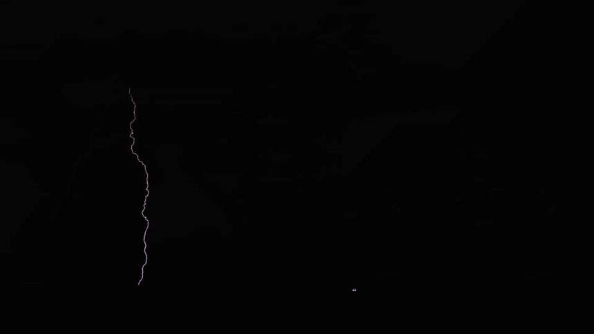 Lightning illuminates the night sky over a desert landscape