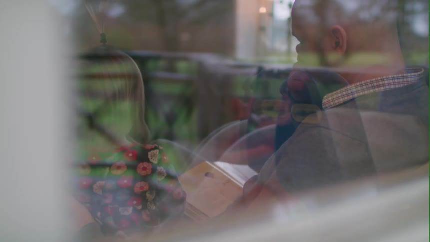 A man reads to his daughter on a couch