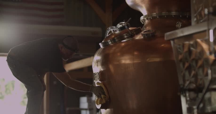 Man polishes large brass kettle