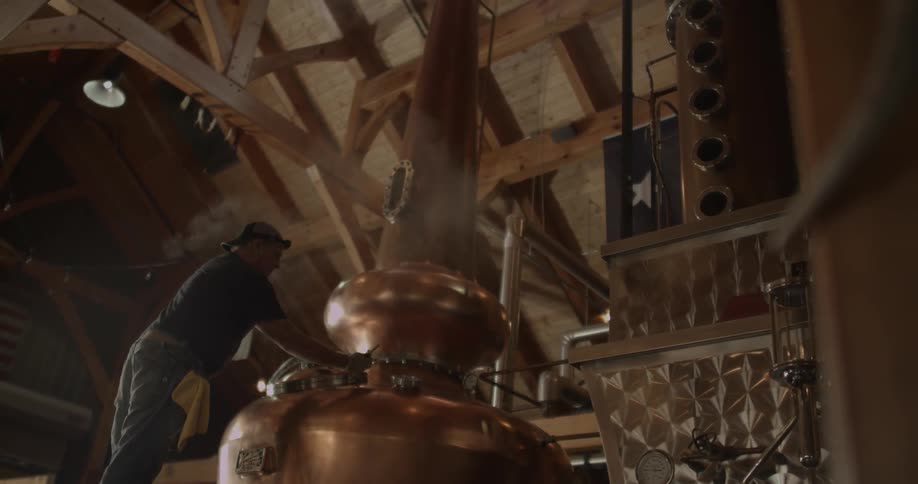 A man checks the gauges on a still