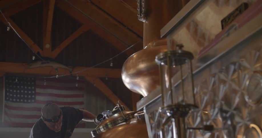 A distillery worker cleans equipment