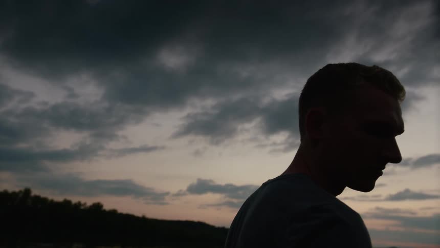 Man stands under dusk sky